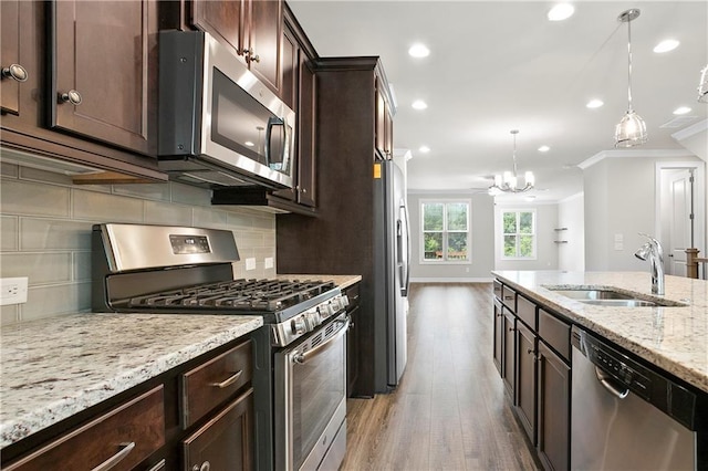 3657 Atherton Park Ct, Suwanee, GA 30024 - kitchen featuring stainless steel appliances, ornamental molding, light wood finished floors, dark brown cabinetry, and decorative light fixtures