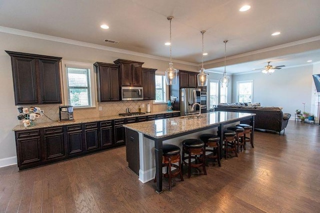 6390 Yellow Birch St, Cumming, GA 30040 - kitchen featuring appliances with stainless steel finishes, a kitchen breakfast bar, dark wood finished floors, open floor plan, and a kitchen island with sink