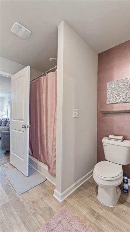 bathroom featuring a shower with curtain, wood-type flooring, and toilet