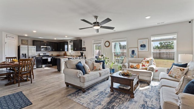 living room with ceiling fan and light hardwood / wood-style flooring