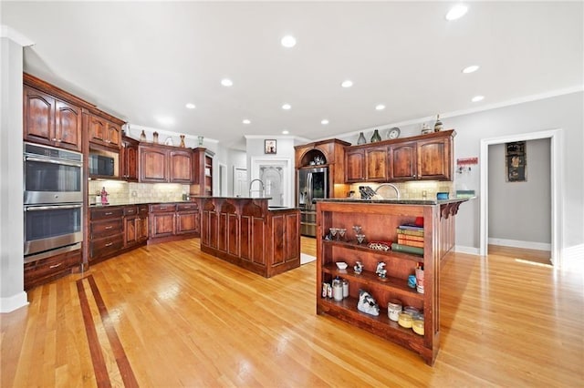 19 Spring Lake Trl NE, White, GA 30184 - kitchen with appliances with stainless steel finishes, an island with sink, a breakfast bar area, tasteful backsplash, and light wood-style flooring