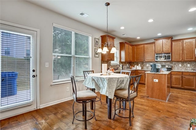 kitchen with visible vents, brown cabinetry, appliances with stainless steel finishes, dark wood-type flooring, and backsplash