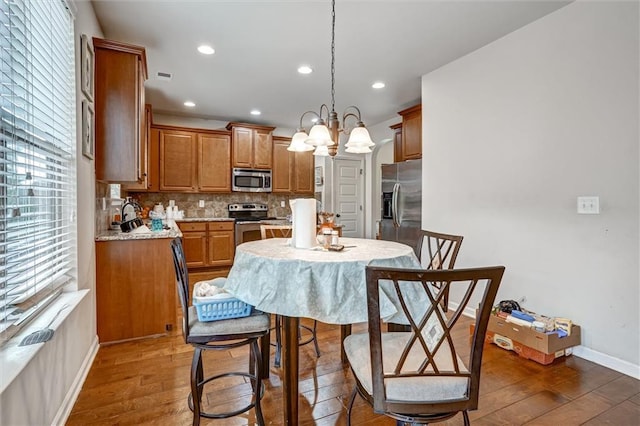 kitchen with tasteful backsplash, brown cabinetry, appliances with stainless steel finishes, light countertops, and a healthy amount of sunlight