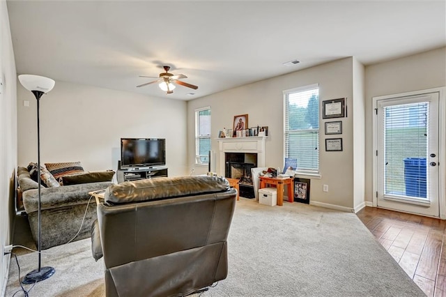 living room featuring ceiling fan, baseboards, wood finished floors, and a glass covered fireplace