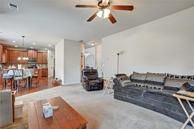 living area with light carpet, visible vents, baseboards, ceiling fan with notable chandelier, and recessed lighting