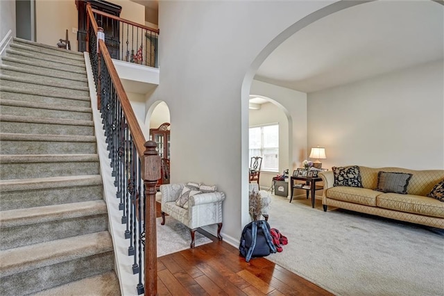 stairs with arched walkways, baseboards, and hardwood / wood-style flooring