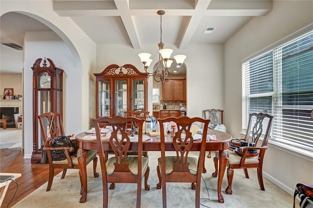 dining area featuring a chandelier, arched walkways, visible vents, and baseboards