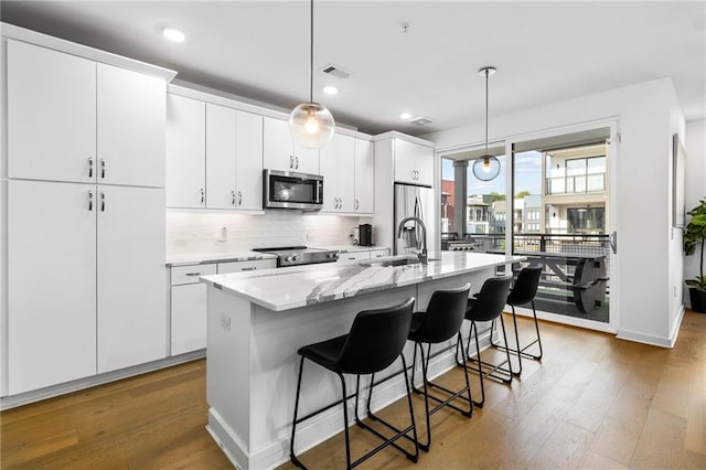 395 Pratt Dr SE Unit No 802, Atlanta, GA 30315 - kitchen featuring stainless steel appliances, a sink, a center island with sink, wood finished floors, and recessed lighting