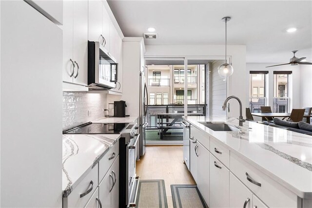 395 Pratt Dr SE Unit No 802, Atlanta, GA 30315 - kitchen with stainless steel appliances, a sink, light wood finished floors, backsplash, and hanging light fixtures