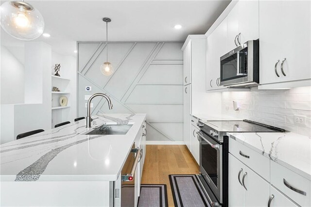 395 Pratt Dr SE Unit No 802, Atlanta, GA 30315 - kitchen featuring stainless steel appliances, a sink, white cabinets, light wood-type flooring, and hanging light fixtures