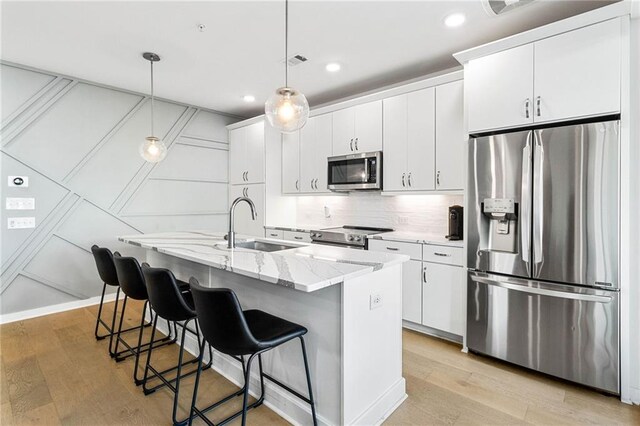 395 Pratt Dr SE Unit No 802, Atlanta, GA 30315 - kitchen with appliances with stainless steel finishes, a sink, light wood-style floors, a kitchen island with sink, and white cabinets