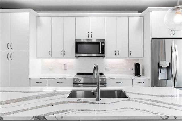 395 Pratt Dr SE Unit No 802, Atlanta, GA 30315 - kitchen featuring appliances with stainless steel finishes, white cabinetry, backsplash, and light stone counters