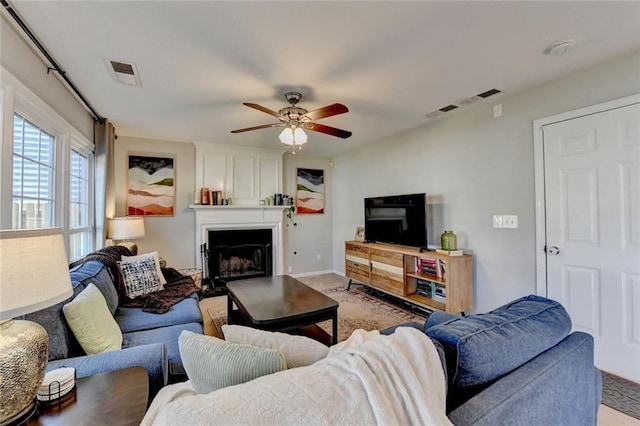 living area featuring light carpet, a large fireplace, visible vents, and a ceiling fan