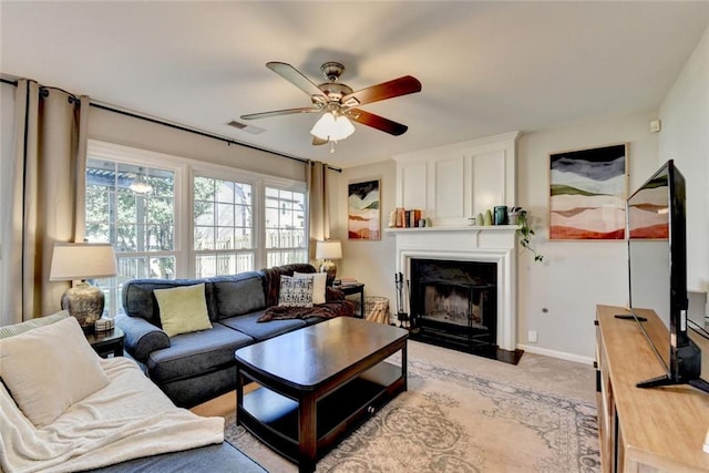 living room featuring light carpet, visible vents, baseboards, ceiling fan, and a fireplace