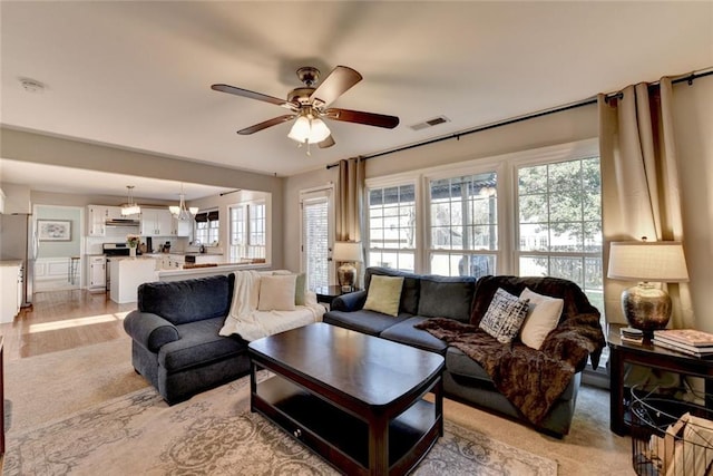 living room with ceiling fan, visible vents, and light wood-style floors