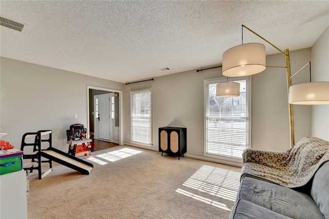 sitting room with a textured ceiling, visible vents, and carpet flooring