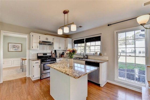 kitchen with visible vents, appliances with stainless steel finishes, white cabinets, a sink, and under cabinet range hood