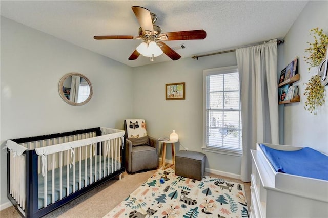 carpeted bedroom with a nursery area, ceiling fan, multiple windows, and visible vents