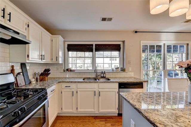 kitchen featuring tasteful backsplash, visible vents, appliances with stainless steel finishes, under cabinet range hood, and a sink