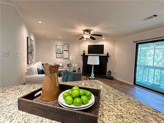 living room featuring ceiling fan, ornamental molding, hardwood / wood-style floors, and a textured ceiling