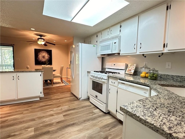 kitchen featuring white appliances, a skylight, white cabinets, ceiling fan, and light wood-type flooring