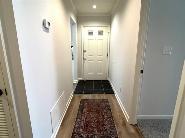 corridor featuring baseboards, wood finished floors, visible vents, and crown molding