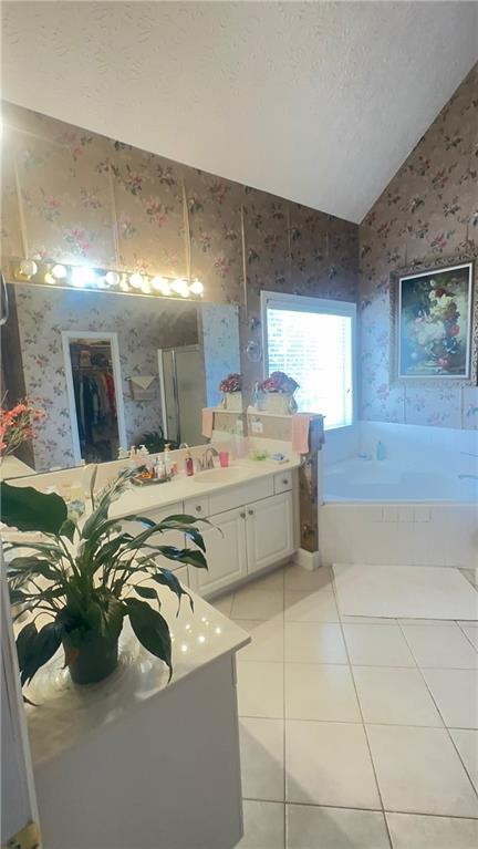 bathroom with tile patterned floors, a textured ceiling, vaulted ceiling, and wallpapered walls