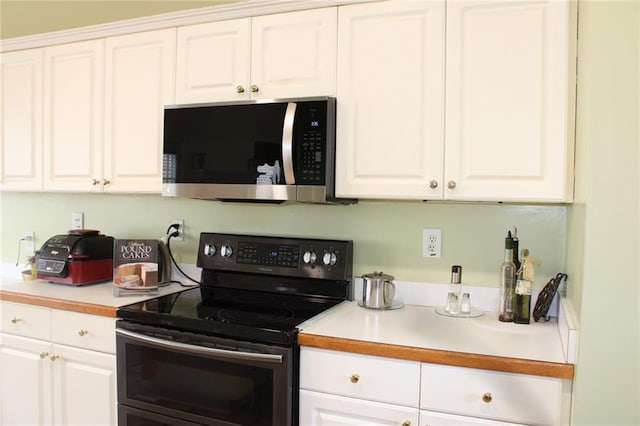 kitchen with white cabinetry, stainless steel microwave, black range with electric stovetop, and light countertops