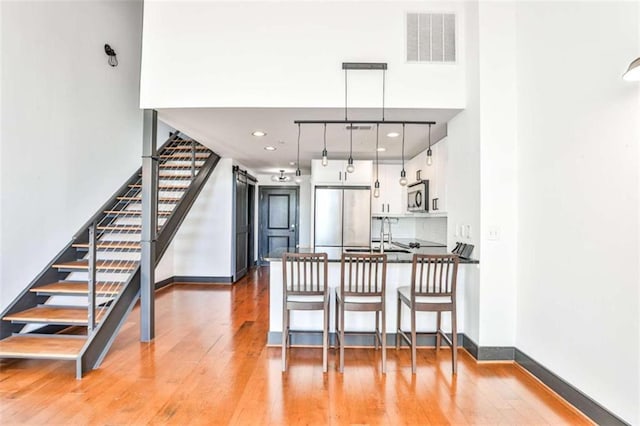 kitchen with light wood-type flooring, visible vents, stainless steel microwave, and built in fridge