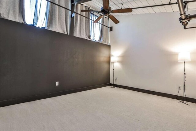 spare room featuring ceiling fan, brick wall, baseboards, beam ceiling, and wood-type flooring