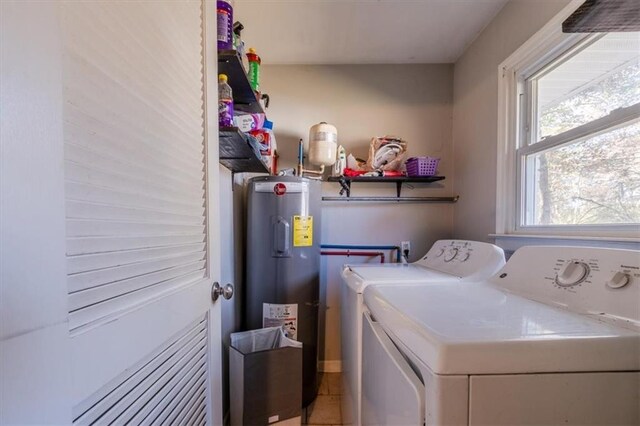 laundry room with water heater, washer and clothes dryer, and tile patterned flooring