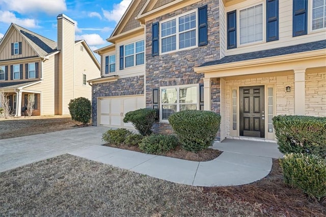 doorway to property with an attached garage, stone siding, and concrete driveway