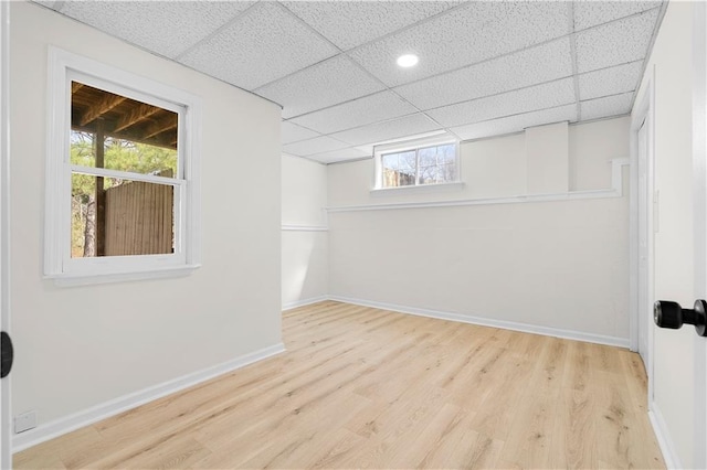 basement featuring a drop ceiling, wood finished floors, and baseboards