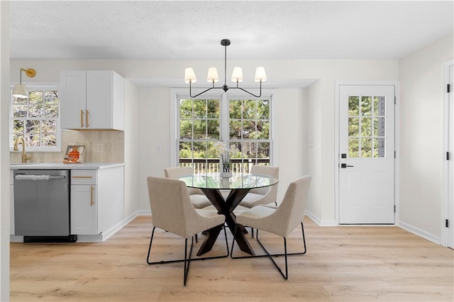 dining space featuring baseboards, a textured ceiling, light wood finished floors, and an inviting chandelier