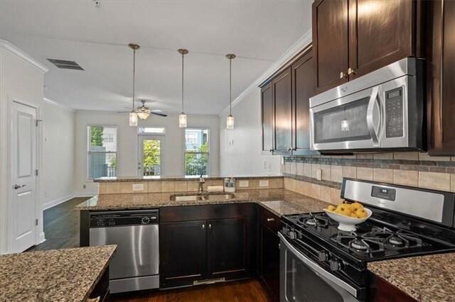 kitchen featuring sink, stainless steel appliances, kitchen peninsula, and light stone countertops