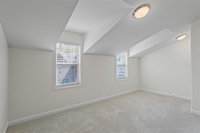 additional living space featuring lofted ceiling and light colored carpet