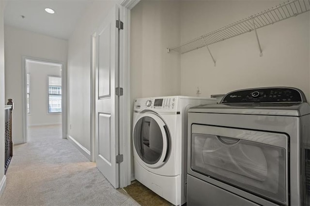 clothes washing area featuring separate washer and dryer and light carpet