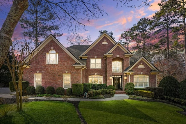 traditional-style home with brick siding and a front lawn