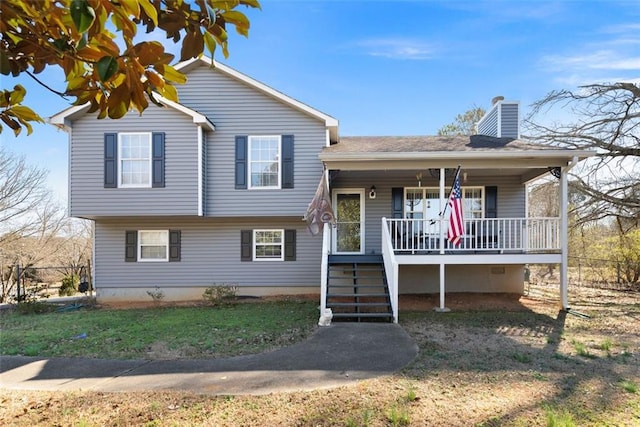 split level home featuring covered porch, a chimney, stairway, and a front lawn