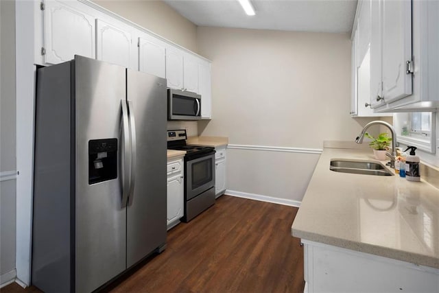 kitchen featuring stainless steel appliances, dark wood-type flooring, a sink, white cabinetry, and light countertops