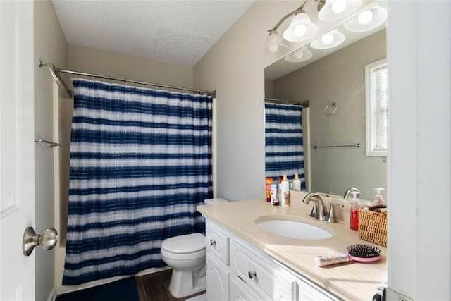 bathroom featuring curtained shower, vanity, toilet, and a textured ceiling