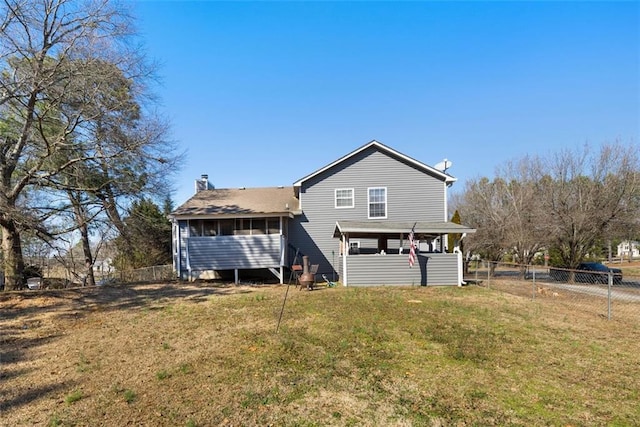 back of house with fence, a chimney, and a lawn