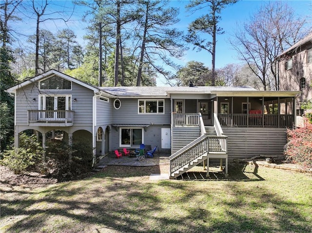 view of front of house featuring a sunroom, stairs, a front lawn, and a patio