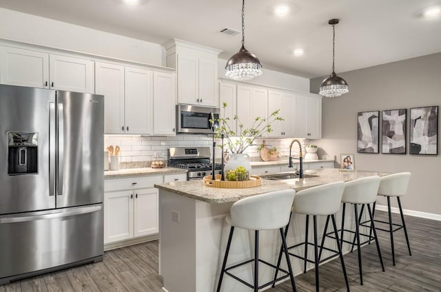 947 Edwin Ln, Sugar Hill, GA 30518 - kitchen with stainless steel appliances, an island with sink, wood finished floors, decorative backsplash, and white cabinets