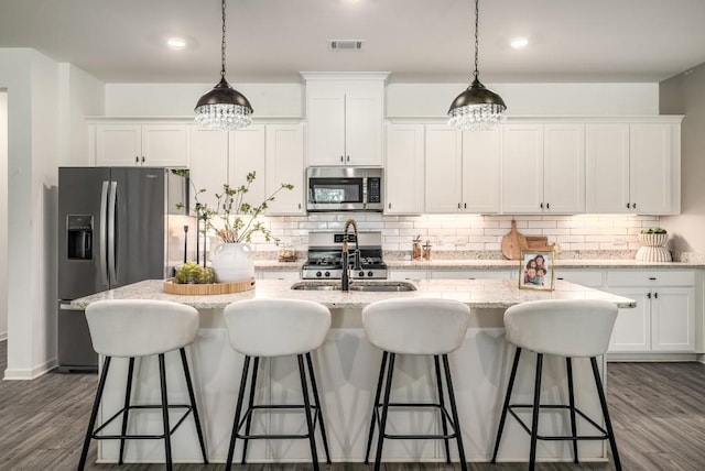 947 Edwin Ln, Sugar Hill, GA 30518 - kitchen featuring appliances with stainless steel finishes, a kitchen island with sink, white cabinetry, and decorative backsplash