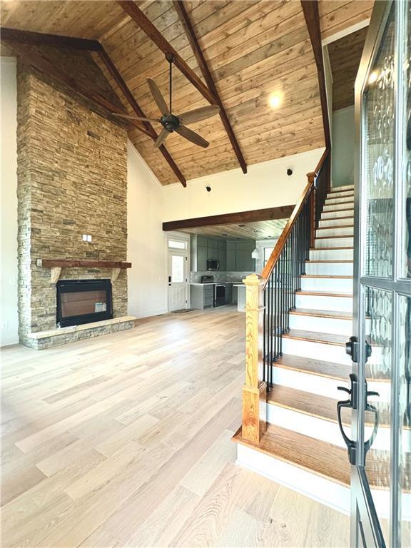 interior space with high vaulted ceiling, a fireplace, hardwood / wood-style flooring, ceiling fan, and wood ceiling