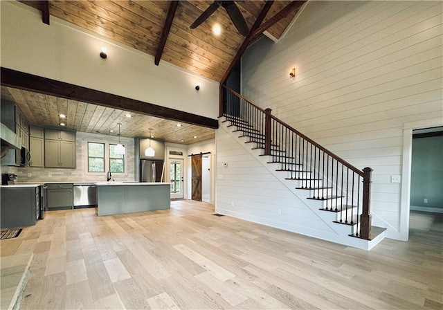 unfurnished living room featuring beamed ceiling, a barn door, wooden ceiling, and light hardwood / wood-style floors