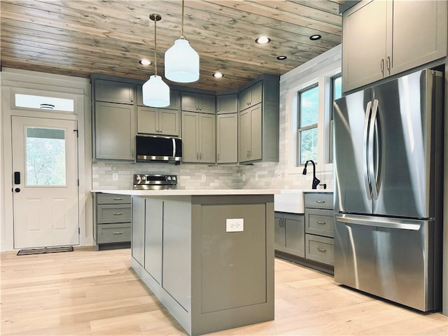 kitchen with a kitchen island, appliances with stainless steel finishes, decorative light fixtures, sink, and wood ceiling