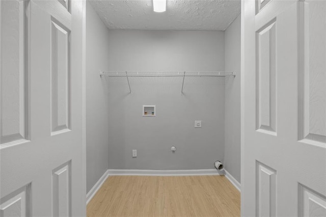 clothes washing area with hookup for an electric dryer, gas dryer hookup, washer hookup, and light wood-type flooring