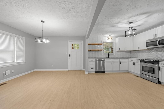 kitchen featuring white cabinetry, decorative light fixtures, stainless steel appliances, and light hardwood / wood-style floors